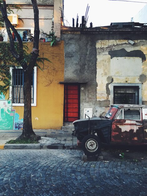 Vello coche dañado en la calle en una zona pobre