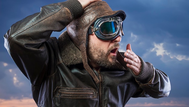 Velocidad, conductor de motor viejo, hombre con chaqueta de cuero de gafas de sol con caras expresivas sobre fondo de nubes de tormenta