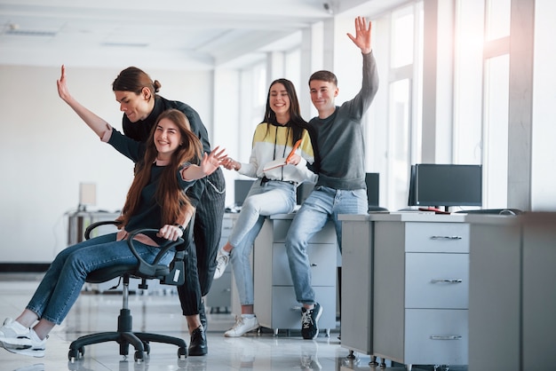 Foto velocidad y sonrisas. divirtiéndose en la oficina. los jóvenes tienen un descanso y conducen utilizando un asiento.