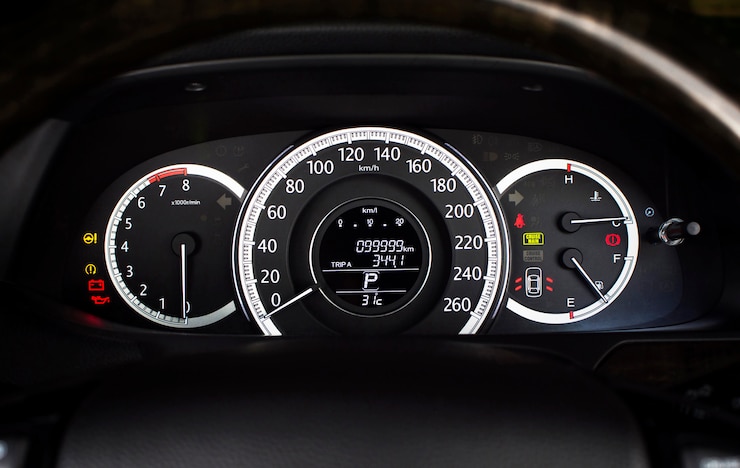 Foto velocímetro de automóvil con kilómetro por hora y tacómetro, medidor de combustible, odómetro y luz de advertencia en el tablero de instrumentos de un automóvil.