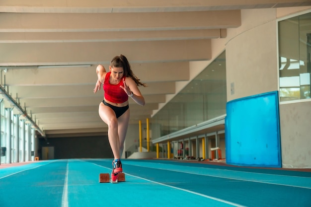 Velocista feminina de atletismo indoor correndo no início da corrida em treinamento