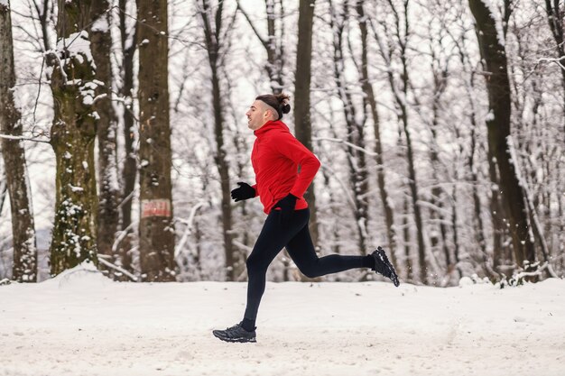 Velocista rápido correndo na floresta na neve no inverno. mais rápido que o vento, vida saudável, preparo físico no inverno