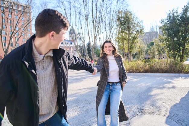 Ven conmigo joven feliz tirando de las mujeres mano a mano concepto de vida moderna sin preocupaciones