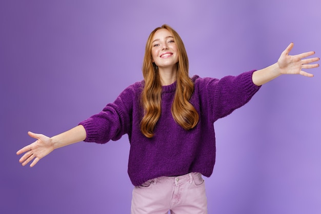 Ven a mis brazos, la chica quiere darte un cálido abrazo. Retrato de mujer pelirroja encantadora amable y linda estirando las manos a través del espacio de la copia y mirando hacia adelante con una sonrisa feliz para abrazar y dar la bienvenida a los invitados.