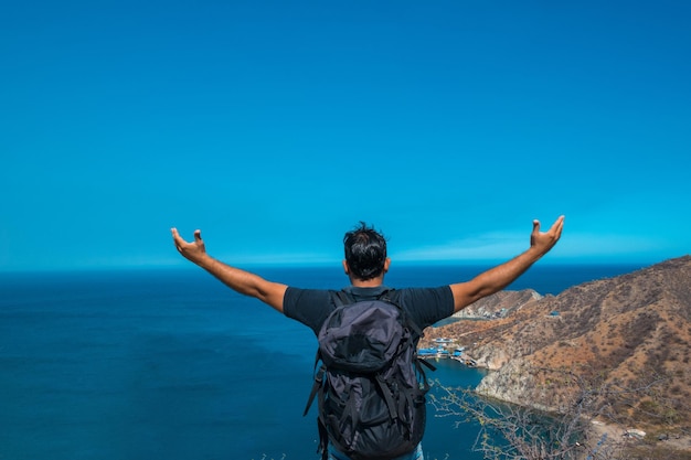 Vencedor/conceito de sucesso. Caminhando homem torcendo euforicamente e alegremente com os braços levantados no céu depois de caminhar até o topo da montanha acima das nuvens.