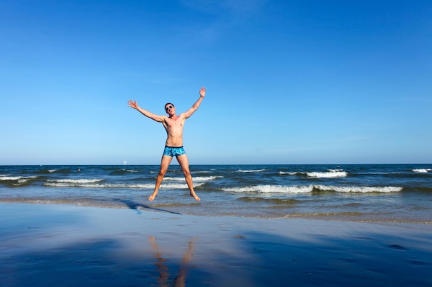 Vencedor do jovem feliz pulando na praia