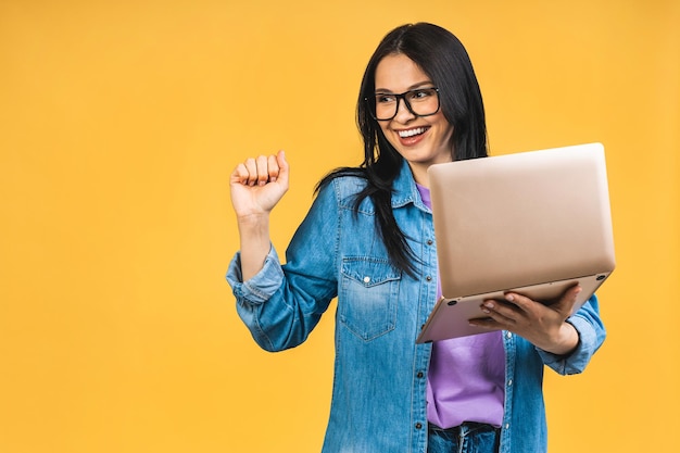 Vencedor feliz Retrato de mulher de negócios sorridente excitada e atraente com laptop isolado sobre fundo amarelo Vencedor com sucesso