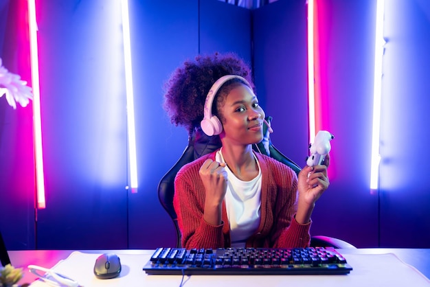 Foto vencedora da equipe de streamers de jogos femininos afro-americanos jogando luta online com esport usando fones de ouvido na sala de iluminação neon conversando com outros jogadores planejando estratégias para vencer os concorrentes tastemaker