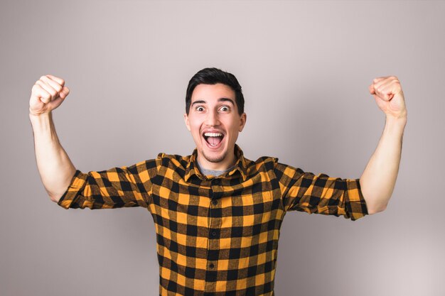 Vencedora. feliz homem animado na camisa amarela comemorando um gesticulando vencedor com os dois braços