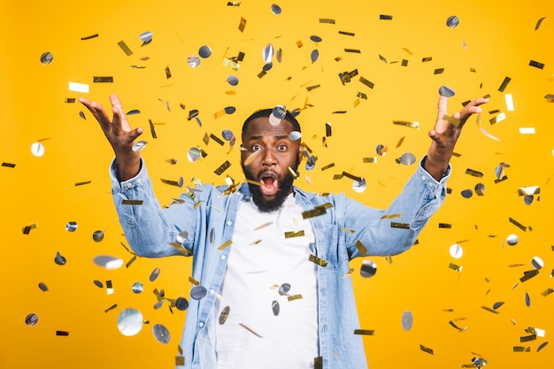 Vencedora! Homem novo afro-americano alegre que dança sobre o fundo amarelo.