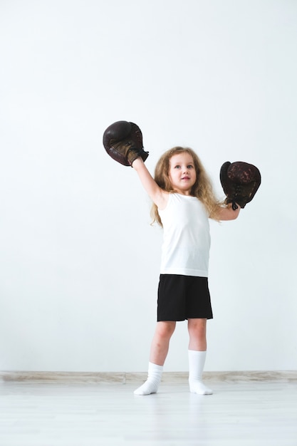 Vencedora. Menina em luvas de boxe.