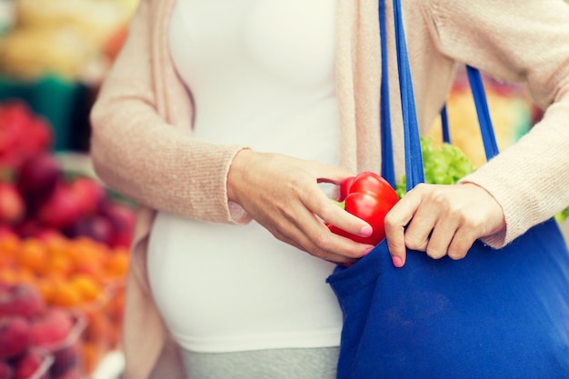 venda, compras, comida, gravidez e conceito de pessoas - close-up de mulher grávida comprando pimenta vermelha ou páprica no mercado de rua