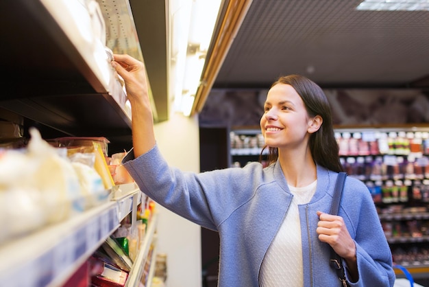 venda, compras, consumismo e conceito de pessoas - jovem feliz escolhendo e comprando comida no mercado