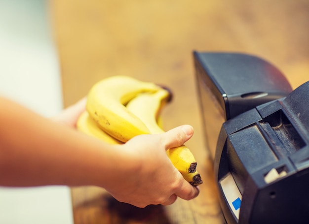 venda, compras, pagamento, consumismo e conceito de pessoas - close-up de mãos comprando ou digitalizando bananas no checkout no mercado de alimentos ou shopping