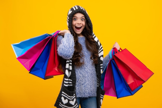 Venda de compras no outono Adolescente espantado Garota adolescente com sacolas de compras isoladas em amarelo