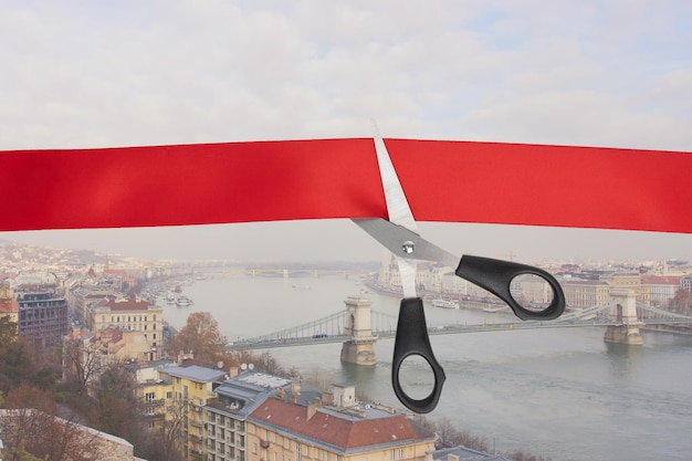 Venda de passagens aéreas Tesouras cortam uma fita vermelha com vista para o rio Danúbio em Budapeste Hungria