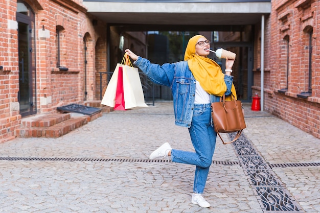 Venda e conceito de compra - feliz garota muçulmana árabe com sacolas de compras depois do shopping