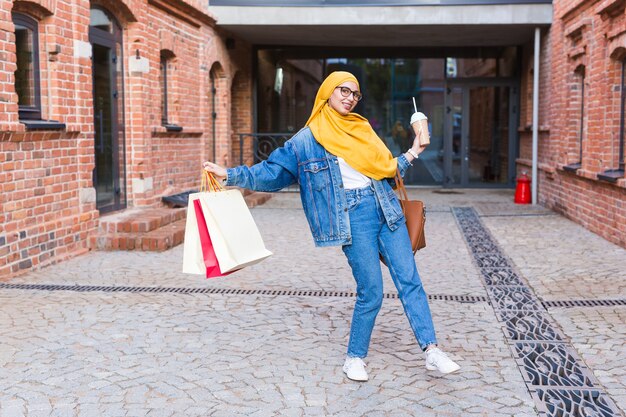 Venda e conceito de compra - feliz garota muçulmana árabe com sacolas de compras depois do shopping