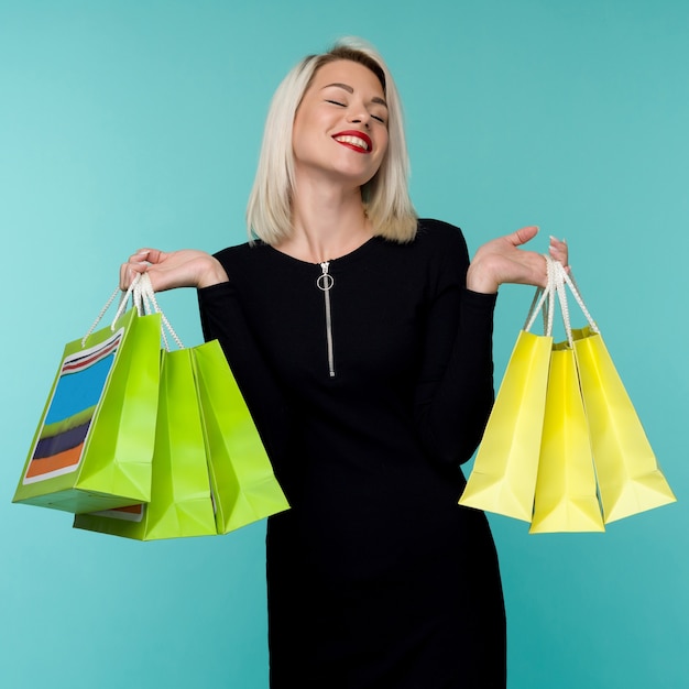 Venda. jovem mulher sorridente segurando sacolas de compras em preto feriado de sexta-feira. garota feliz no azul