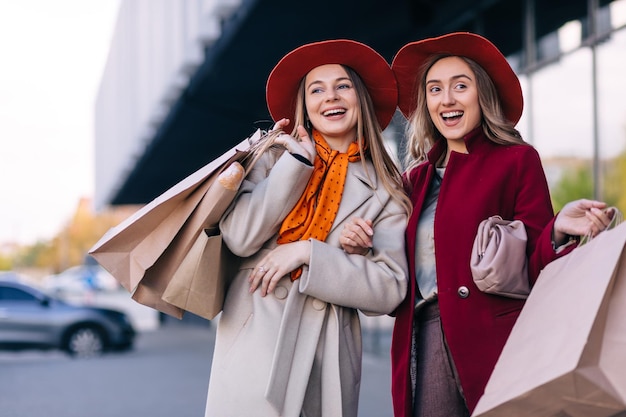 Venda mulheres jovens felizes com sacolas de compras andando pela rua da cidade