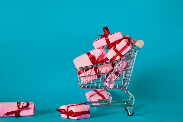 Vendas de férias, conceito. Muitas caixas de presente rosa no carrinho de compras.