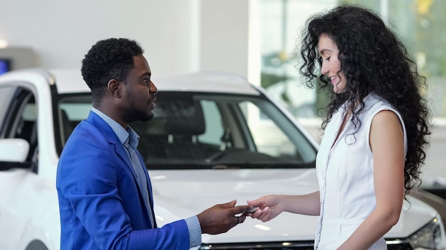 Vendedor afro-americano dá a chave do carro comprado ao cliente