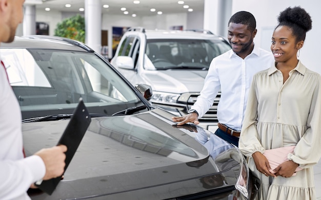 Vendedor amigável e lindo casal africano no showroom de carros