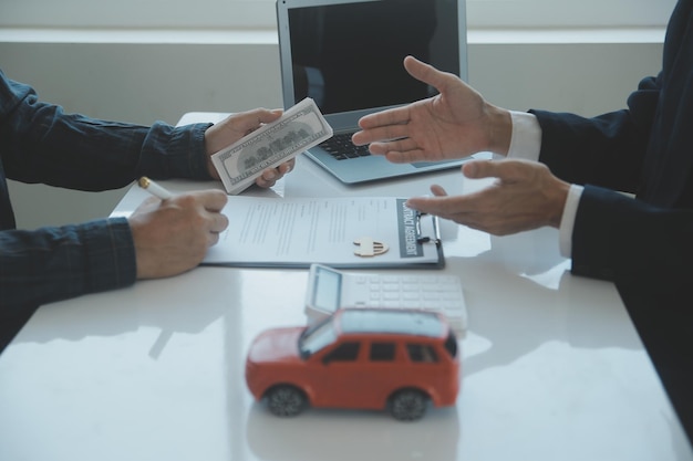 El vendedor de automóviles o el gerente de ventas de los hombres asiáticos de primer plano se ofrece a vender un automóvil y explica y lee los términos de la firma de un contrato de automóvil y un seguro