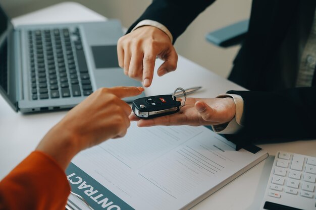 Un vendedor de automóviles o gerente de ventas de hombres asiáticos de primer plano ofrece vender un automóvil y explica y lee los términos de la firma de un contrato de automóvil y un seguro