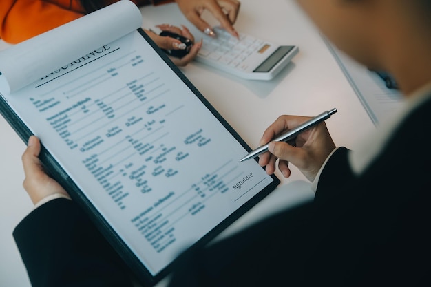 El vendedor de automóviles o el gerente de ventas de los hombres asiáticos de primer plano se ofrece a vender un automóvil y explica y lee los términos de la firma de un contrato de automóvil y un seguro