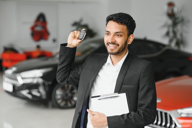 Foto vendedor de autos alegre indio en la sala de exposición