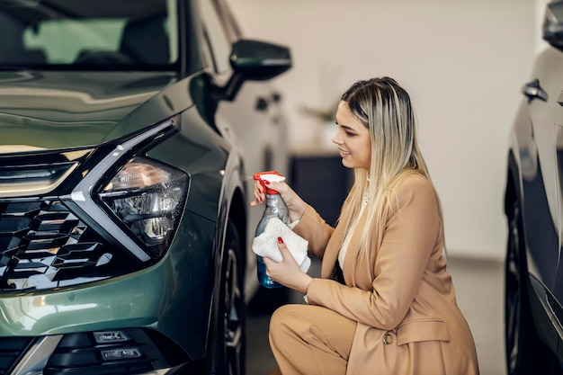 El vendedor de autos feliz está limpiando autos en la sala de exposición