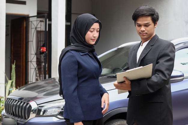 Vendedor de autos llenando documentos con su cliente musulmán en el concesionario