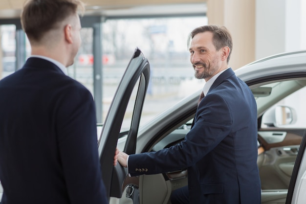 Vendedor de autos profesional ayudando a su cliente a elegir un auto nuevo