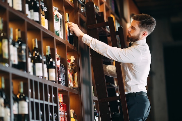 El vendedor de bebidas clasifica las botellas de pie en la escalera.