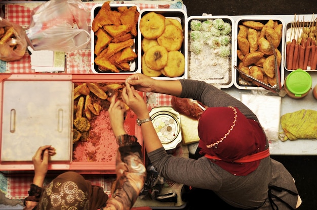 Foto vendedor de chef filipino que cocina comida callejera local al estilo filipino en una tienda de vendedores ambulantes a la venta filipinos y clientes viajeros extranjeros comen bebidas en la plaza intramuros de maynila en manila, filipinas