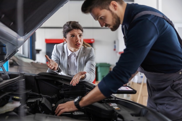 Foto vendedor de coches hablando con un mecánico que está arreglando el coche