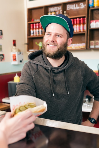 vendedor com cachorro-quente em lanchonete de fast food