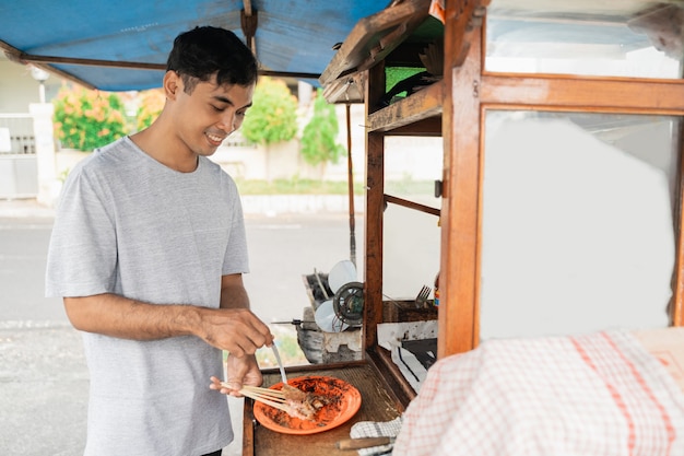 Vendedor de comida tradicional preparando la comida para el cliente