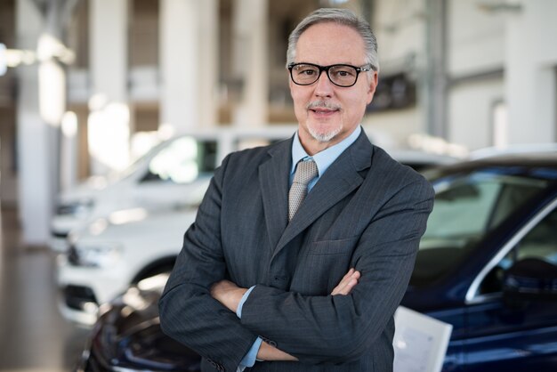 Vendedor de un concesionario de automóviles frente a un automóvil en su sala de exposición.