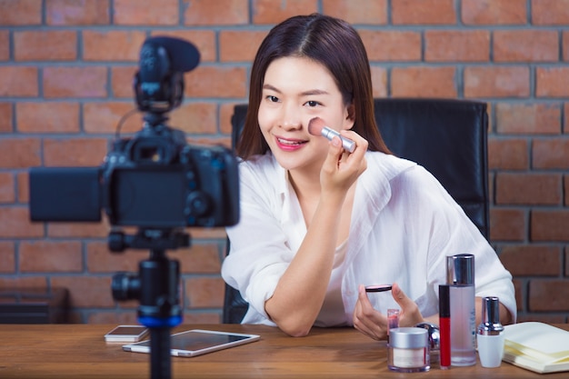 Vendedor cosmético en línea joven de la mujer asiática vlogging para mostrar cómo hacer maquillaje