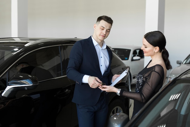 El vendedor le da al comprador las llaves de un auto nuevo en la sala de exposición