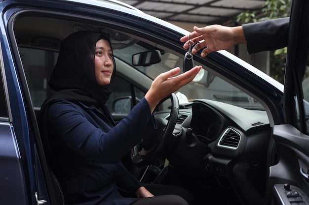 El vendedor le da las llaves del auto a una mujer musulmana después de un exitoso acuerdo minorista en el centro de concesionarios