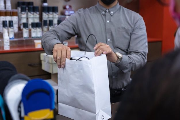 Vendedor dando bolsa de compras al cliente en la tienda