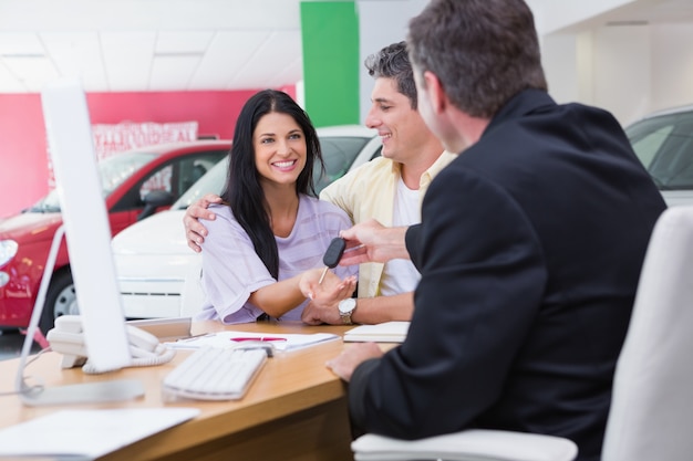 Vendedor dando las llaves del coche a una pareja