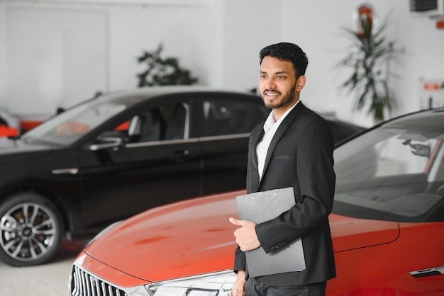 Vendedor de carros indiano alegre mostrando carro novo no showroom