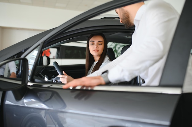 Vendedor de carros mostrando ao cliente um carro novo e falando sobre seu desempenho
