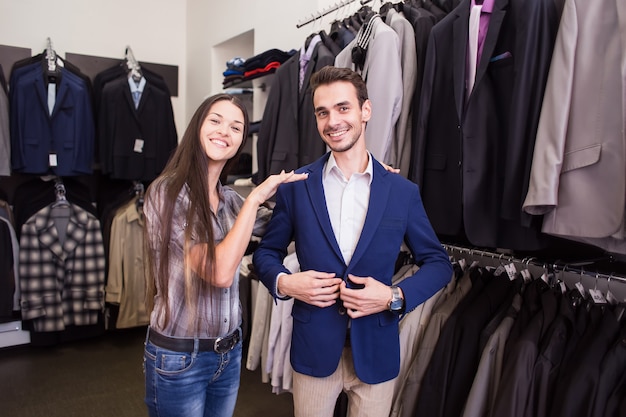 Vendedor de menina ajuda a pegar um cliente em uma boutique de roupas masculinas de jaqueta