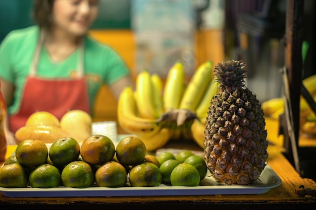 Vendedor de menina tailandesa vende frutas, bananas, mangas, tangerinas e abacaxis em uma loja de conveniência na rua Khao Lak.