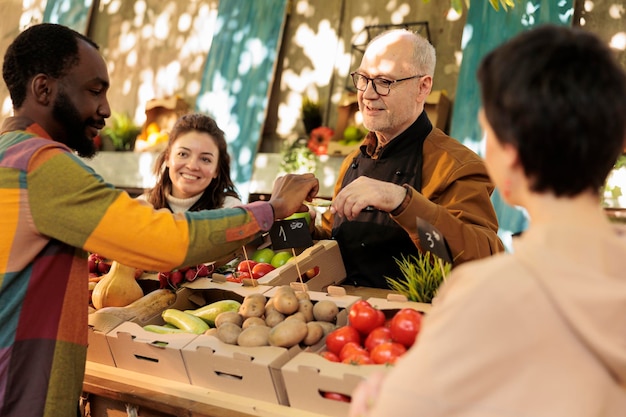 Foto vendedor de mercado de agricultores oferecendo aos clientes pedaços de frutas cortadas enquanto fazem compras no mercado de agricultores. idoso amigável proprietário de estande de fazenda local oferecendo aos consumidores para experimentar o produto antes de comprá-lo